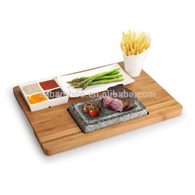 bamboo serving platter with grill stone and three ceramic side dishes